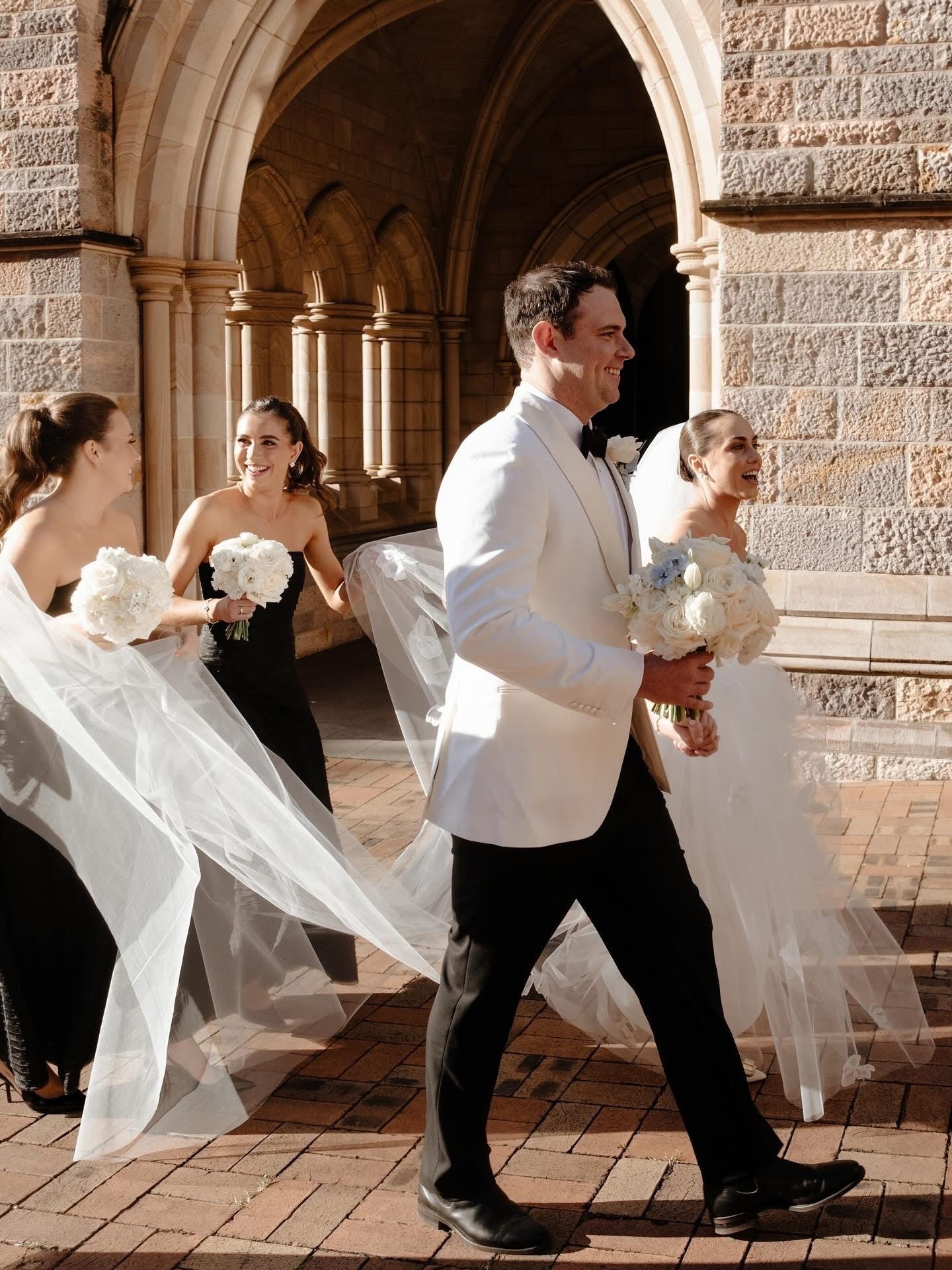 Wedding party walking together in front of a stone building
